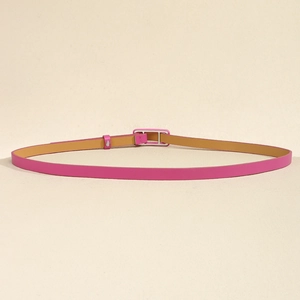 Détail d'une fine ceinture en cuir rose pêche avec boucle rectangulaire argentée et doublure