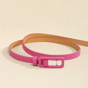 Détail d'une ceinture fine fuchsia avec boucle carrée assortie et intérieur en cuir tan