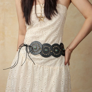 Detail of bohemian black leather belt with turquoise discs and studs over a lace dress