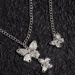 Collier chaîne argentée avec pendentifs papillon détaillés sur un fond noir élégant