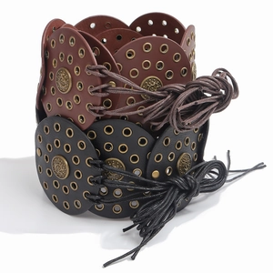 Detailed view of vintage wide waist belt with metal eyelets and embossed medallions