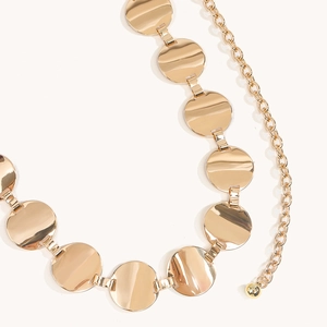 Detailed macro view of gold-tone geometric metal waist chain with polished round plates