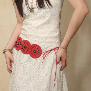 Detail of red bohemian waist belt with turquoise inlays and rivets on white lace dress