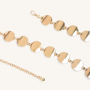 Detail view of gold geometric chain belt with polished discs and adjustable lobster clasp