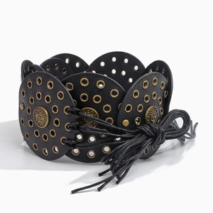 Detail of western style black leather belt with metal eyelets and vintage round discs