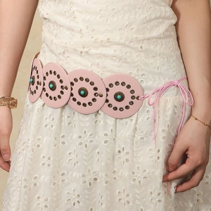 Close-up of pink modular belt with turquoise stones and bronze rivets on white lace dress