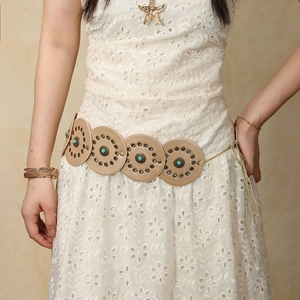Close-up of bohemian leather belt with turquoise stones and brass rivets on lace dress