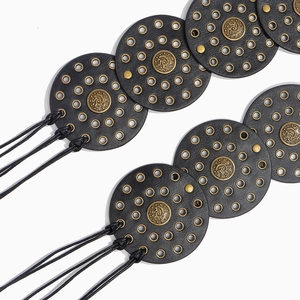 Detailed close-up of retro Western style belt featuring round leather discs and bronze eyelets
