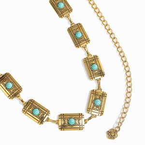 Macro detail of vintage gold chain belt with turquoise stones and floral pendant charm