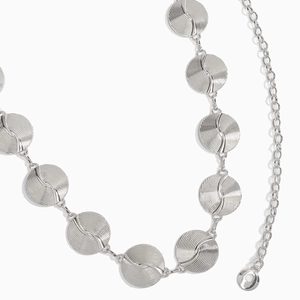 Macro view of silver metal waist chain featuring textured circular disks and lobster clasp