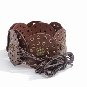 Detail of vintage brown leather belt with bronze metal eyelets and embossed medallions