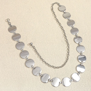 Detail of silver geometric round disc waist chain with lobster clasp and ball charm