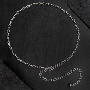 Dettaglio catena in argento con maglie a cuore e pendente a sfera in metallo lucido