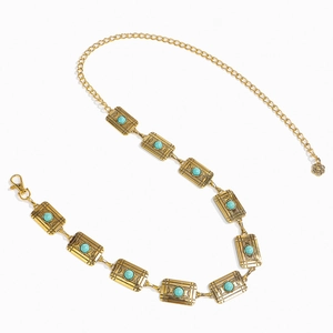 Detailed macro view of vintage gold metal waist chain with carved turquoise stone beads