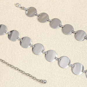 Close-up of polished silver metal waist chain featuring round disks and lobster clasp