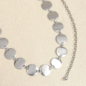 Close-up of a silver geometric metal waist chain featuring round polished discs and links