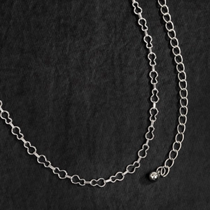 Dettaglio delle maglie in metallo argentato a forma di orso su una catena minimalista in vita