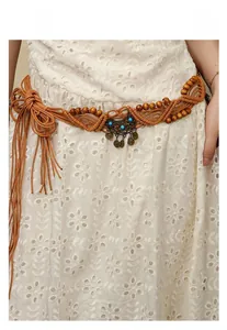 Detail of bohemian woven waist belt with bronze pendants and beads on white lace dress