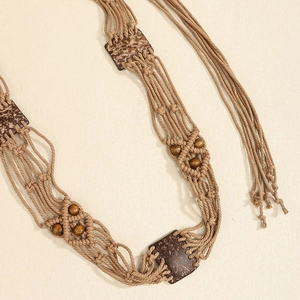 Détail de ceinture tressée bohème avec perles en bois et glands ethniques sur fond beige