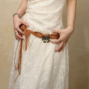Detail of bohemian woven waist chain with turquoise pendant and moon tassels on white dress
