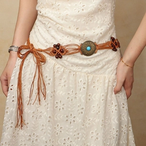 Detail of bohemian braided waist chain with turquoise buckle on a white dress