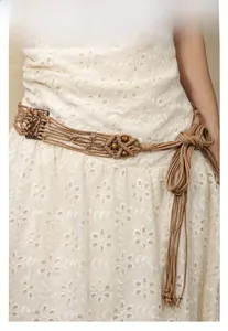 Gros plan sur la ceinture bohème tressée avec perles ethniques sur robe brodée blanche