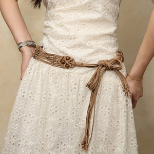 Détail d'une ceinture tressée bohème avec perles en bois sur une robe d'été blanche