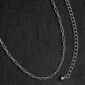 Dettaglio della catena a vita a maglie ondulate argento con anelli e pendente a sfera