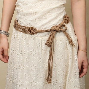 Détail de ceinture tressée bohème avec perles en bois et glands sur une robe blanche