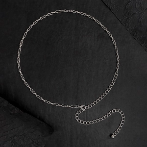 Dettaglio della catena in metallo argentato per la vita con maglie cave e pendente a sfera