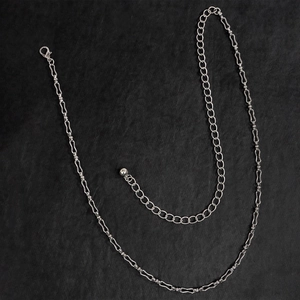 Dettaglio della catena da vita in metallo argento con maglie oblunghe e chiusura a moschettone