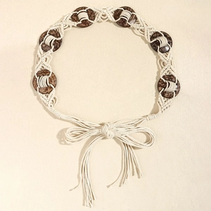 Détail de ceinture tressée en macramé avec coquilles de coco et longs glands