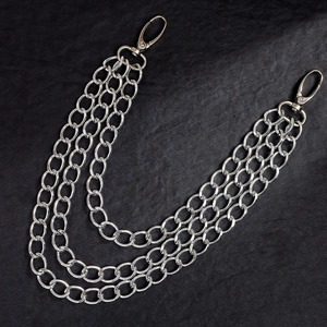 Three-layer silver metal pants chain with lobster clasps on a dark textured background