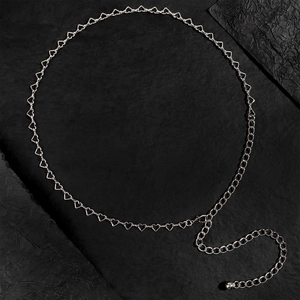 Dettaglio macro della catena in vita argento con maglie a cuore su sfondo nero strutturato