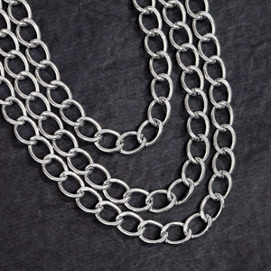 Close-up of three-layer polished silver metal chains on a black stone background
