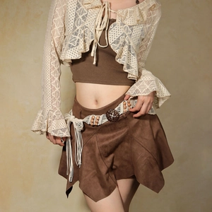 Détail d'une ceinture tressée bohème avec glands sur une jupe en daim et cardigan