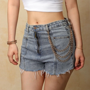Close-up of triple-layered gold metal chains on light blue frayed denim shorts