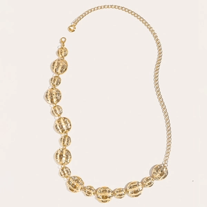 Detailed macro view of a gold metallic chain with hollow circular textured plates