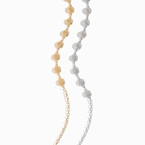 Detailed macro view of minimalist gold and silver metal chain belts with hollow round beads