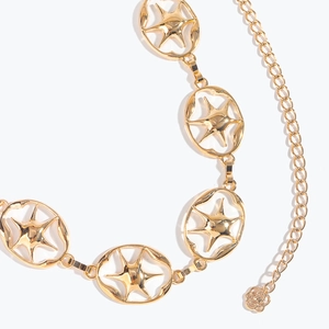 Détail de la ceinture chaîne dorée à étoiles gravées montrant les maillons et pendentif