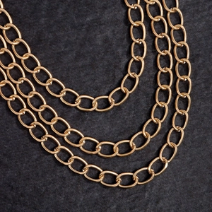 Three-layer gold punk waist chain for jeans featuring oval links on grey rock background