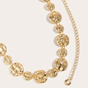 Detailed close-up of textured gold metal discs and chain links of a luxury waist belt
