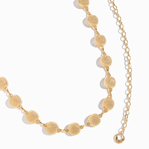 Close-up of golden metal waist chain with hollow textured mesh spheres and hook