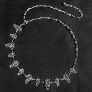 Detailed macro view of silver coffin charms with skull relief on gothic metal chain belt