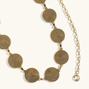 Vue détaillée d'une chaîne de taille dorée avec des charmes circulaires à texture spirale