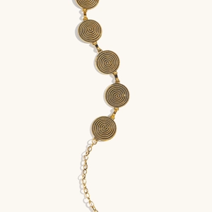 Détail de la chaîne de taille dorée avec disques à texture spirale et lien ajustable