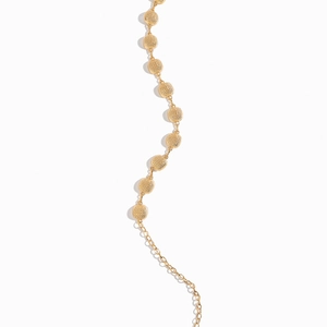 Detail of elegant gold chain featuring textured metal beads for dress or shirt accessories