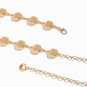 Detail view of gold chain belt featuring hollow mesh textured round beads and lobster clasp