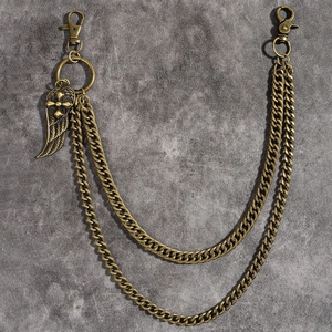 Detailed macro view of vintage brass double trouser chain with feather and cross pendant