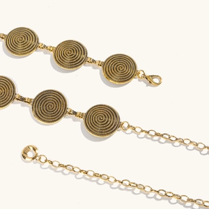 Détail d'une chaîne de taille dorée avec disques texturés en spirale embossée